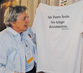 Daughter of Charity Sr. JT Dwyer displays a T-shirt hanging in the LCWR Region XII: Family Detention booth, one of the exhibitors at the assembly. In English on the other side, the shirt says: 